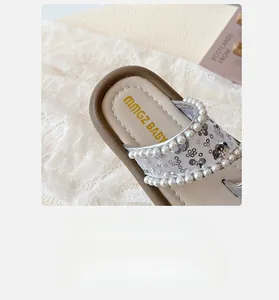 Détail de sandales pour filles avec paillettes argentées et perles sur la bride