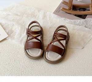 Detail view of brown leather toddler sandals with crisscross straps and rubber soles