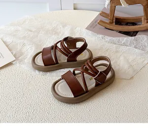 Detail of brown faux leather girls' sandals featuring cross straps and soft cushioned soles
