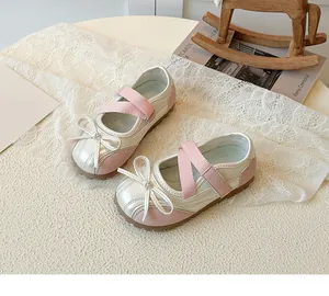 Close-up of pink and beige Mary Jane shoes with bow detail and elastic straps