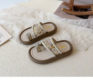 Gros plan de sandales dorées pour filles avec paillettes, perles et fleurs d'orteils
