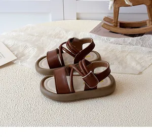 Detailed shot of dark brown leather kid sandals with velcro straps and cross straps