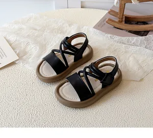 Detail of kids sandals featuring black crisscross straps and velcro closure on beige base
