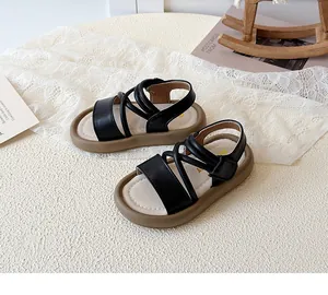 Close-up of black leather girls' sandals with criss-cross straps and flexible beige soles