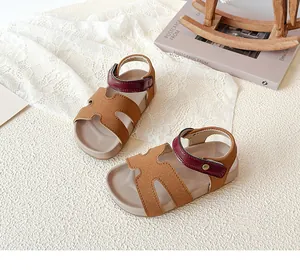 Detail of kids open-toe sandals featuring brown H-cutout upper and burgundy ankle strap