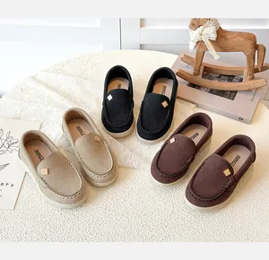 Close-up of suede kids loafers in black, beige and coffee colors with metal buckles