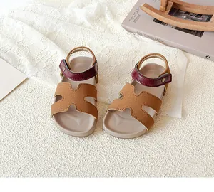 Close-up of girls' cutout sandals featuring H-shaped brown strap and burgundy buckle