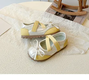 Detail of yellow and silver Mary Jane shoes with bow and crisscross straps for girls