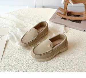Detailed view of khaki suede kids loafers with classic stitching and metal emblem