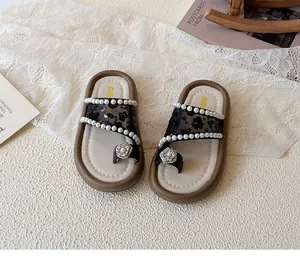 Détail de sandales pour filles avec dentelle noire et ornements de perles blanches