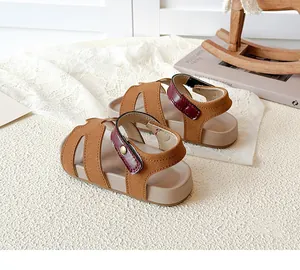 Detail of brown suede kids' sandals with burgundy ankle straps and hollow-out design