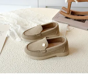 Detailed close-up of khaki suede loafers with diamond metal buckle and stitching