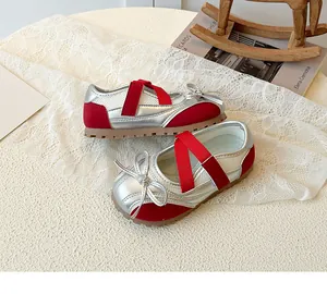 Detail of silver Mary Jane sneakers for girls with red straps and bow decoration