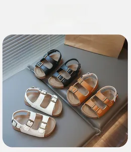 Détail de sandales enfant en noir, blanc et marron avec boucles métalliques réglables