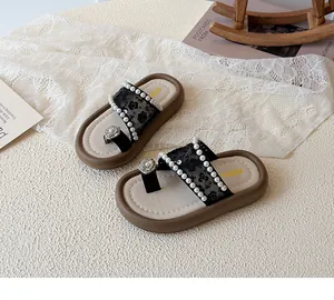 Détail de sandales entre-doigts en dentelle noire pour filles avec fleur en perles