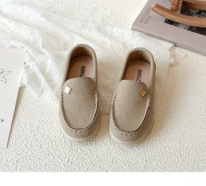 Close-up of beige suede kids' loafer with gold metal accent and stitched leather edge