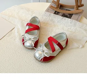 Detail of silver and red Mary Jane shoes for girls featuring a metallic bow and elastic straps
