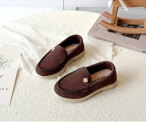 Close-up of brown suede kids loafer showing gold buckle and artisan stitching details