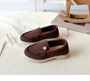 Close-up of brown suede loafers for kids with metal buckle and non-slip beige rubber sole