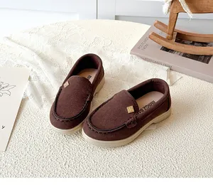 Detailed shot of dark brown suede loafers for kids with soft soles and gold buckle detail
