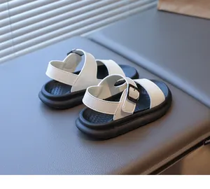 Dettaglio di sandali per bambini con cinturini in pelle bianca e suole nere antiscivolo
