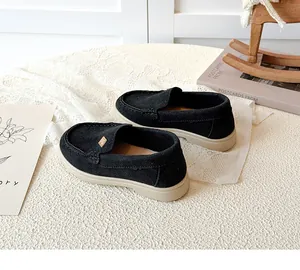 Detail of black suede kids' loafers with gold square ornament and beige rubber sole