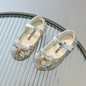 Sparkly silver girls Mary Jane princess shoes with sequin bow on a textured glass surface