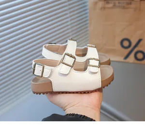 Détail de sandales blanches pour enfants avec trois boucles métalliques réglables en bronze