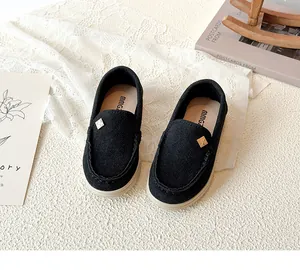 Close-up of black suede loafers for kids with golden hardware in a vintage setting