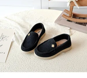 Close-up of black suede loafers for kids with non-slip rubber sole and golden buckle