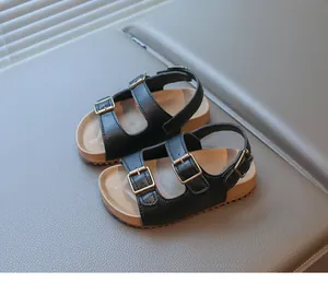 Détail de sandales noires pour enfants avec boucles en bronze et semelle en liège