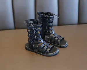 Close-up of black gladiator sandals for girls featuring lace-up cage design and zippers