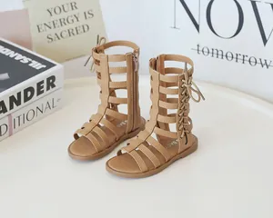 Detail view of girls' Roman high-top sandals in camel with lace-up bow and side zipper