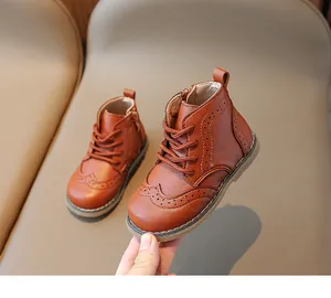 Detail of caramel brown leather kids boots with brogue carving and side zipper closure