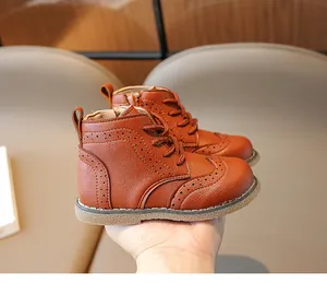 Detail of children's brown leather mid-top boots with side zipper and brogue patterns