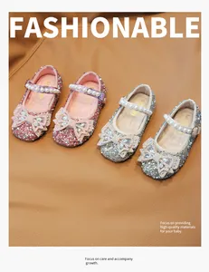Detalle de zapatos brillantes para niña con lazo de pedrería y tira de perlas