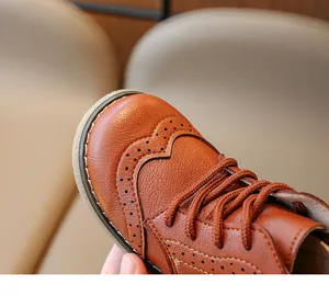 Close-up of brown leather children's boots with detailed Brogue style carvings and stitching