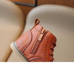 Detail of brown leather kids' boots featuring side zipper and brogue decorative perforations