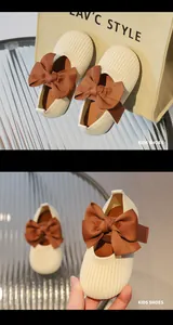 Details von cremefarbenen Strick-Mary Janes mit brauner Schleife und weicher Sohle