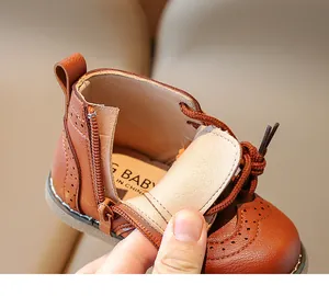 Detail of brown leather baby boots with side zipper and brogue decorative punching