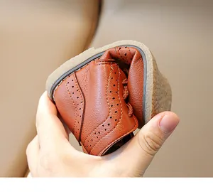 Detail showing highly flexible caramel leather kids shoe with brogue patterns and gum sole
