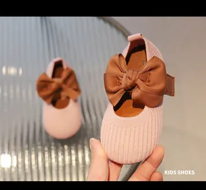 Nahaufnahme der rosa gestrickten Mädchenschuhe mit brauner Schleife und Klettverschluss