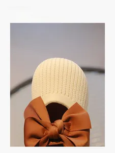 Detail eines gestrickten Prinzessinnenschuhs für Kinder mit großer brauner Satinschleife