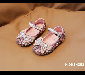 Detalle de zapatos rosa con purpurina para niñas con lazo de cristal y perlas