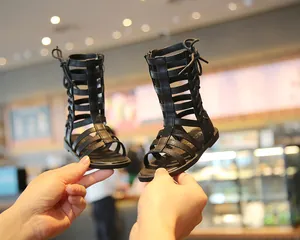 Detailed view of girls black gladiator sandals with cross strap and high-top design