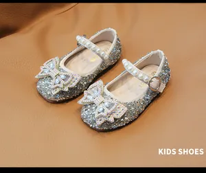 Detalle de zapatos de princesa plateados para niña con lazo de strass y perlas