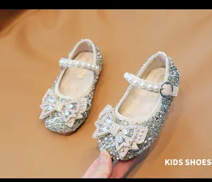 Detalle de zapatos de princesa para niña con lentejuelas plata, lazo de strass y perlas