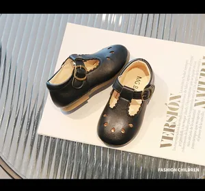 Detalle de zapatos T-strap infantiles con calados decorativos y hebilla de metal vintage