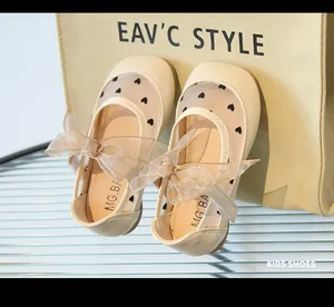 Dettaglio di scarpe Mary Jane beige da bambina con motivi a cuore e fiocco in tulle