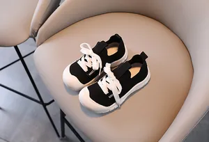 Detailed macro of kids' sneakers featuring breathable black knit mesh and white laces